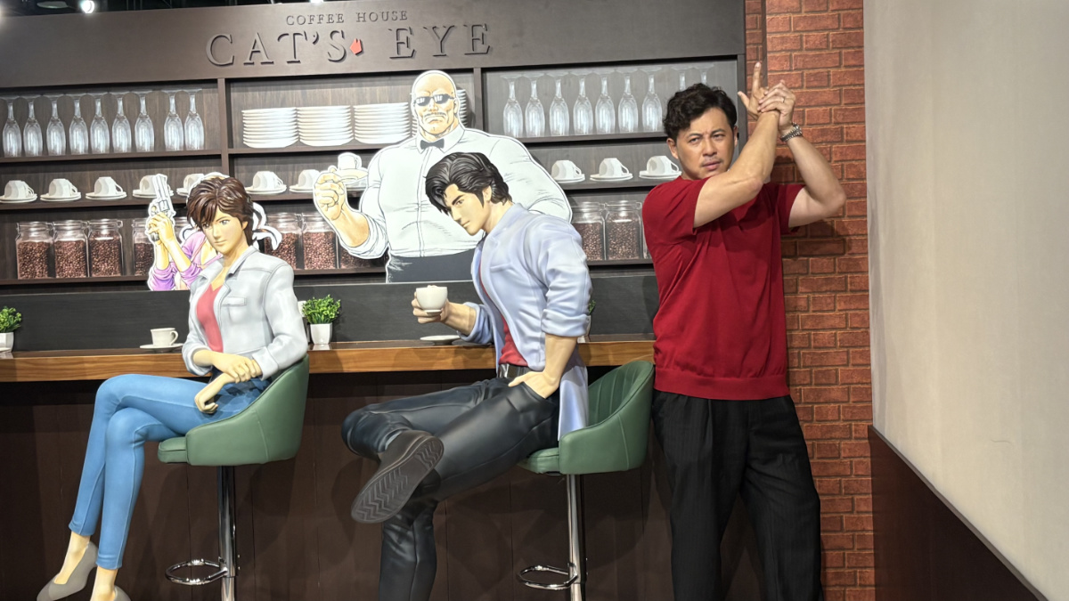 喫茶キャッツアイの展示前で銃を構えるポーズを取る平子祐希さん
