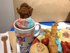 ラムネとイチゴのソフトクリームにミャクミャク焼きが乗っているデザート