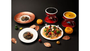 ハロウィンの飾り付けを背景に並ぶパスタやチーズフォンデュなどの料理